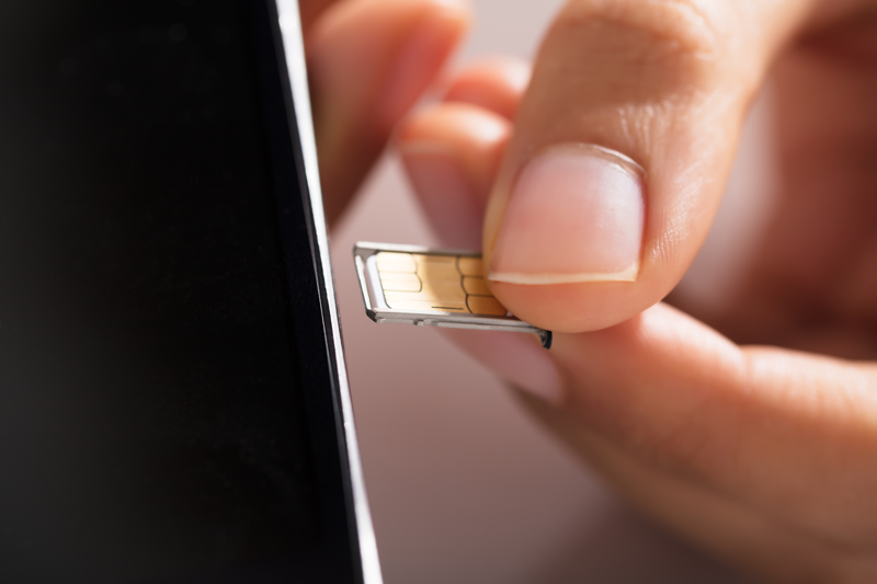 Close de uma mão trocando o chip de um celular
